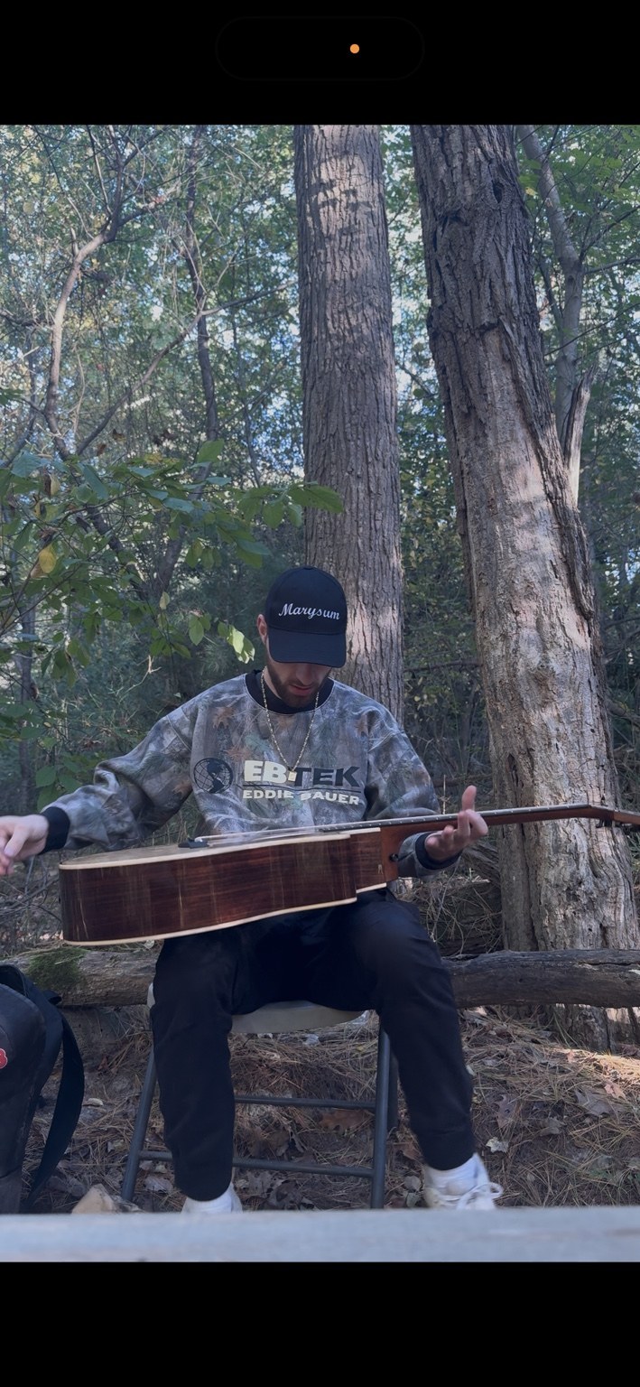 Neec outdoors holding a guitar
